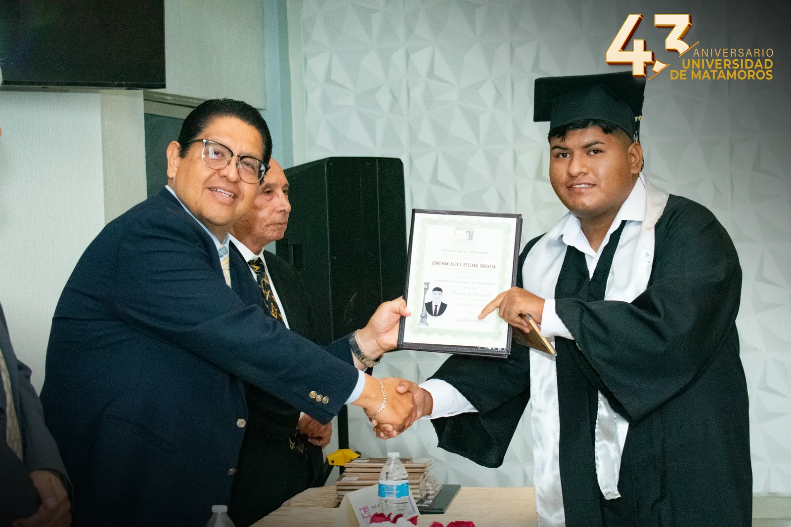 Un egresado recibe su carta de pasante en la graduación de Ingeniería en Sistemas y Automatización.